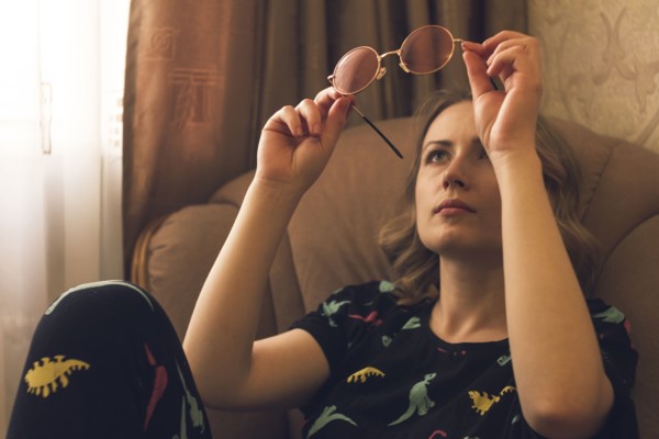 Caucasian woman sitting in armchair examining sunglasses