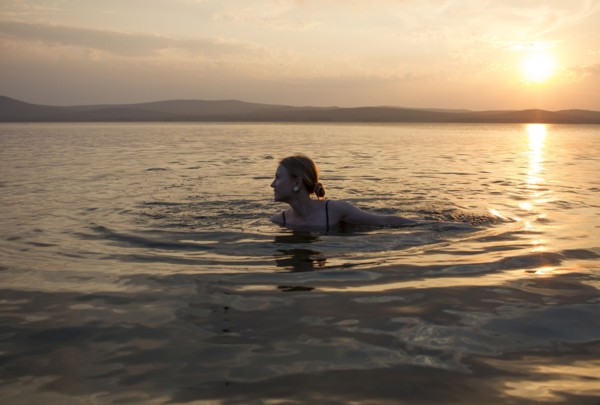Caucasian woman swimming in lake at sunset