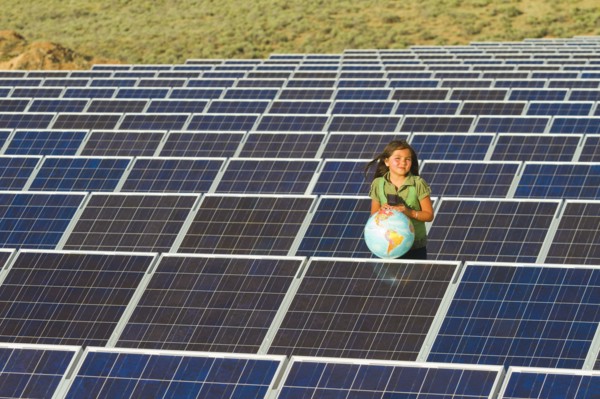Native American girl standing near solar panels holding globe