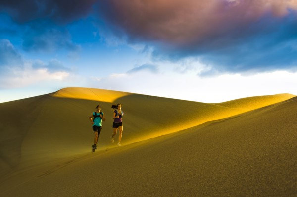 Hispanic couple running on sand dune