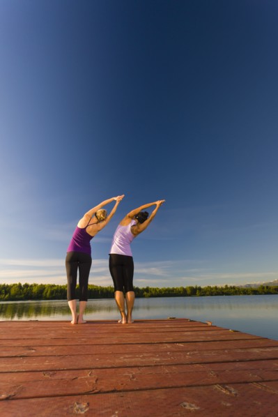 Woman practicing yoga on lake pier