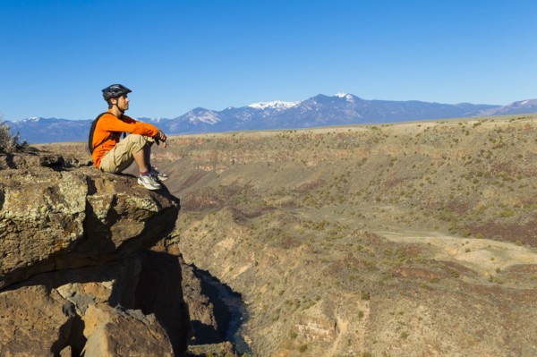 Hispanic man sitting on canyon cliff