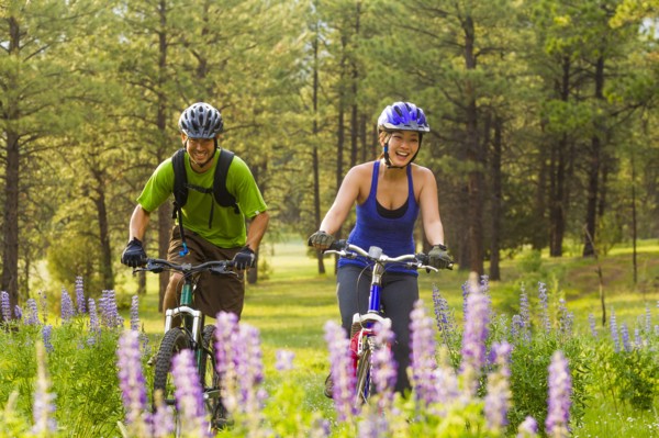 Couple riding mountain bikes in meadow