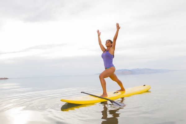 Filipino woman practicing yoga on paddle board