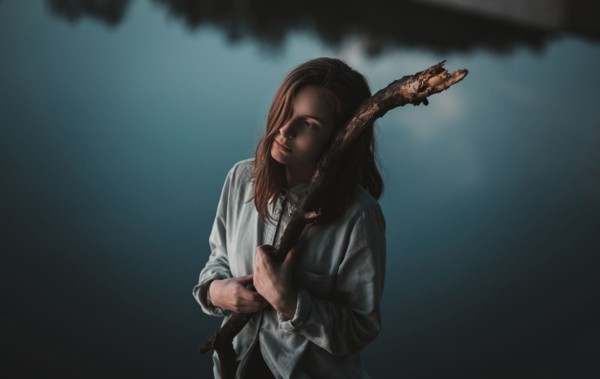 Caucasian woman holding stick near still lake