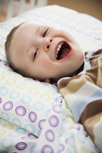 Laughing Caucasian boy laying in bed
