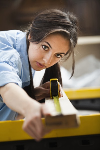 Caucasian woman measuring wood