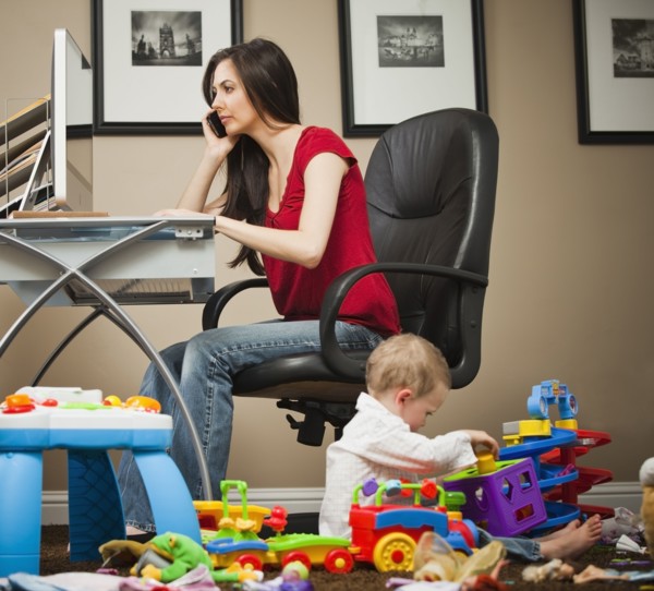 Caucasian woman tending child and working in home office