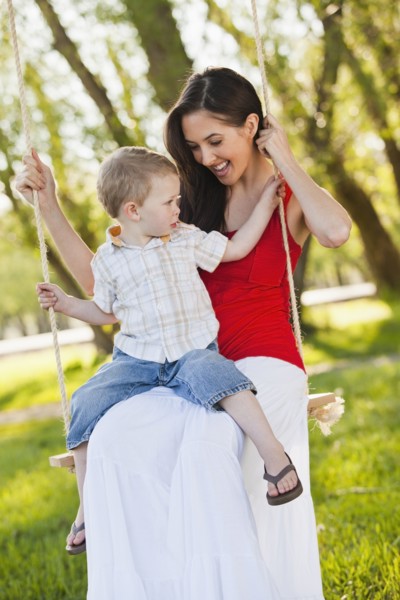 Caucasian mother and son swinging together