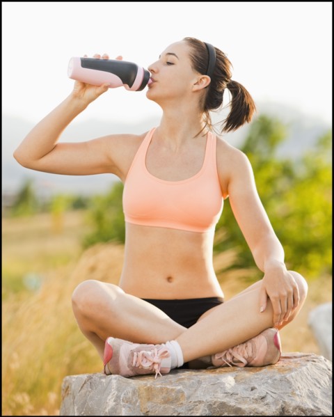 Caucasian woman drinking water after workout