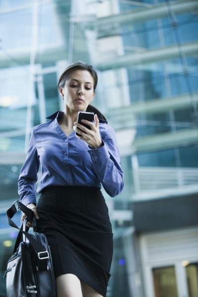 Caucasian businesswoman looking at cell phone outdoors