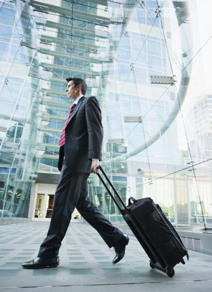 Caucasian businessman pulling suitcase outdoors