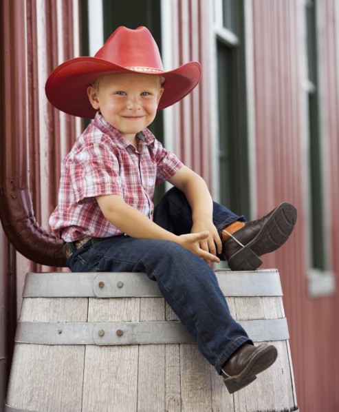 Caucasian cowboy sitting on barrel