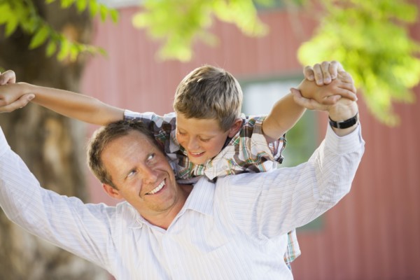 Caucasian father carrying son on his shoulders