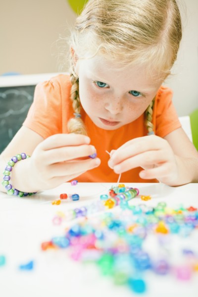 Caucasian girl stringing beads