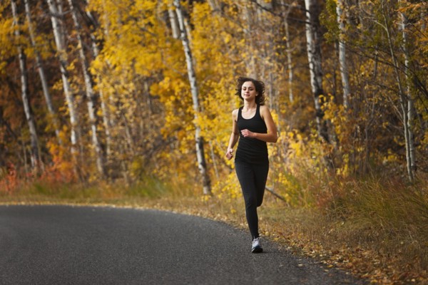 Caucasian woman running along autumn road