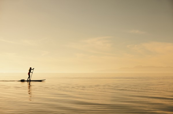 Caucasian woman standing on paddle board