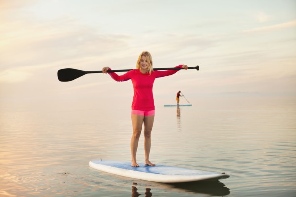 Caucasian woman standing on paddle board
