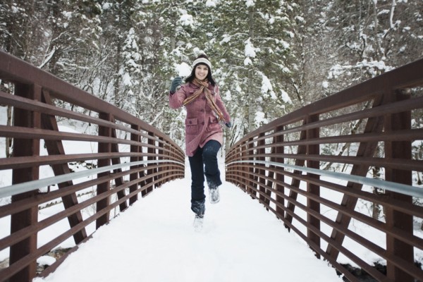 Caucasian woman crossing snow covered bridge