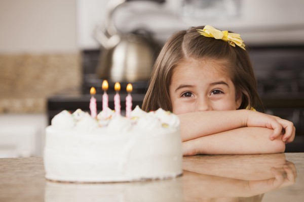 Caucasian girl looking at birthday cake
