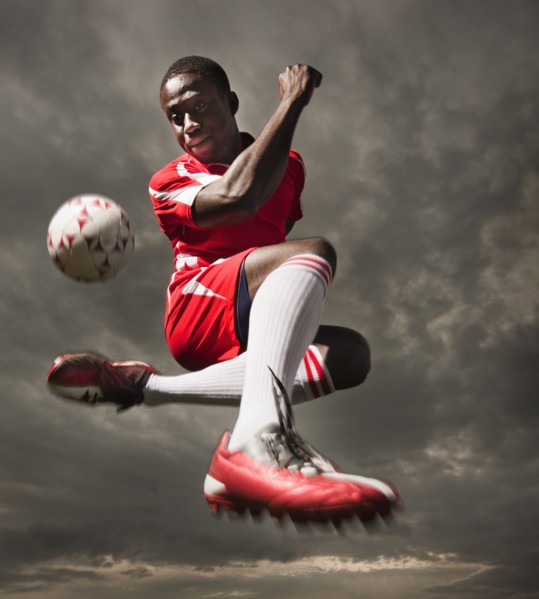 Black soccer player kicking ball