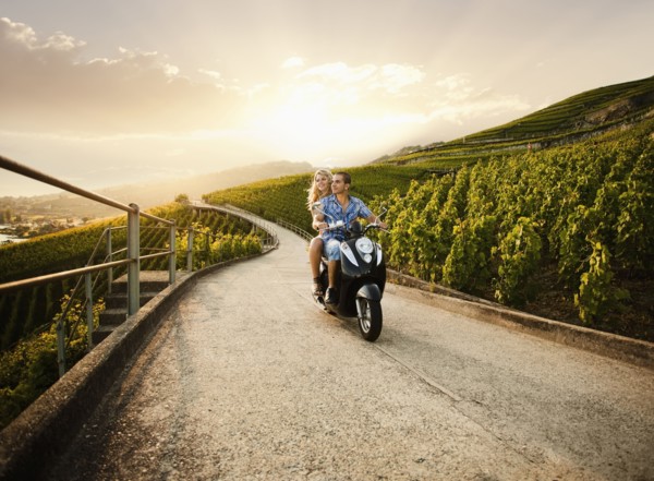 Couple riding scooter in vineyard