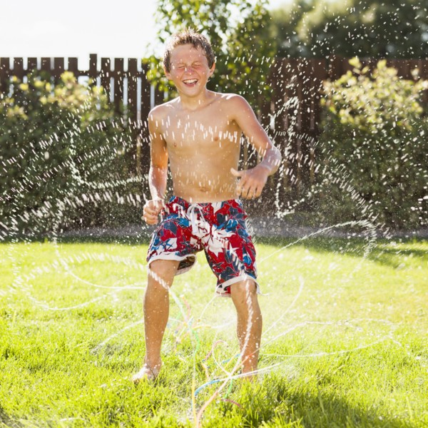 Caucasian boy playing in sprinkler