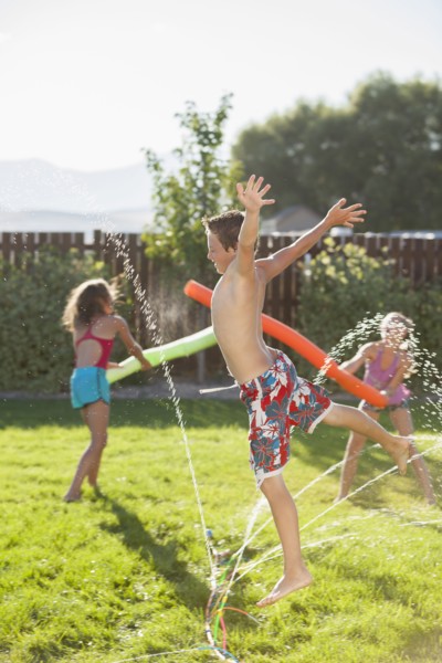 Caucasian children playing in the sprinkler