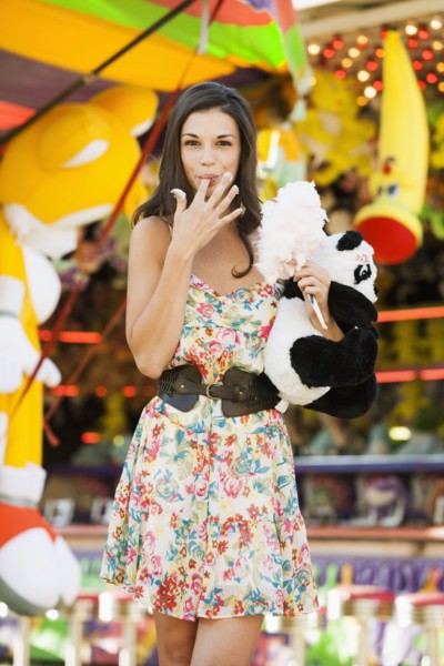 Caucasian woman eating cotton candy at carnival