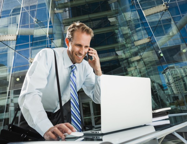 Caucasian businessman talking on cell phone at laptop