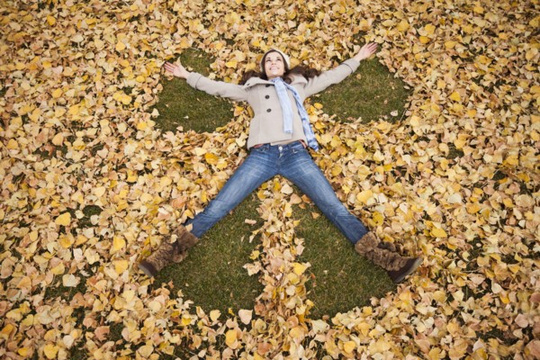 Caucasian woman making angel in autumn leaves