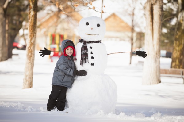 Caucasian boy building snowman in snow