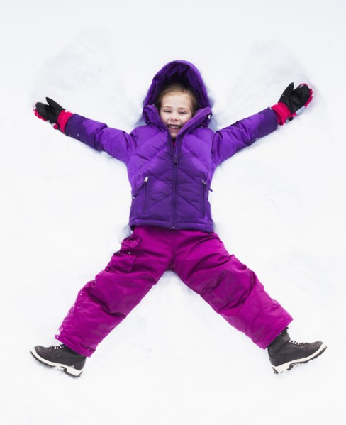 Caucasian girl making snow angel outdoors