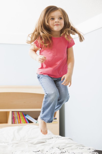 Caucasian girl jumping on bed