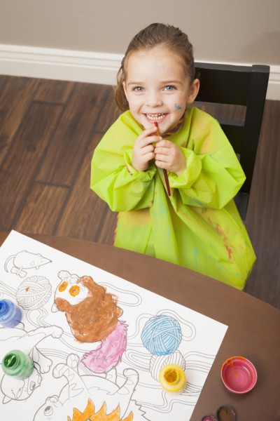 Caucasian girl painting at table