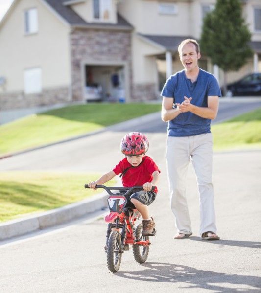 Caucasian father teaching son to ride bicycle
