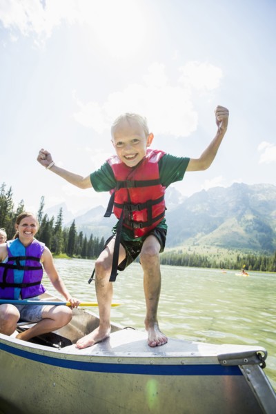 Caucasian boy standing on canoe on lake