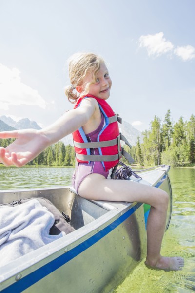 Caucasian girl sitting on top of canoe on lake