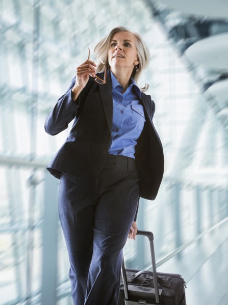 Caucasian businesswoman rushing with suitcase in airport