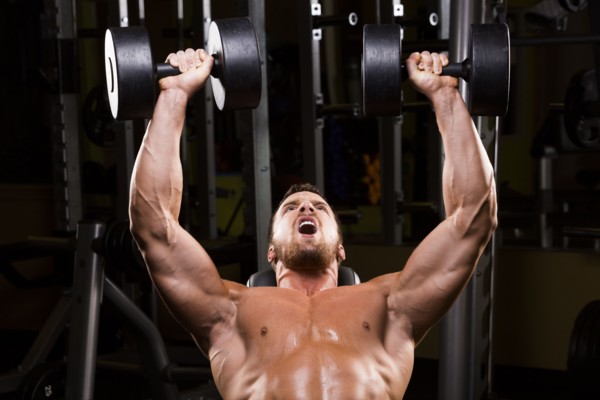 Caucasian man doing incline chest presses with dumbbells in gym
