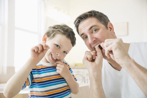 Caucasian father and son flossing their teeth