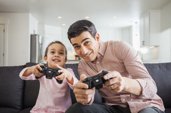 Father and daughter playing video games in living room