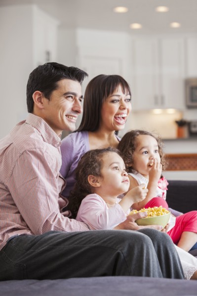 Family watching television together on sofa