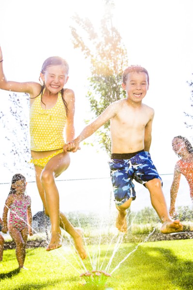 Caucasian children playing in sprinkler in backyard
