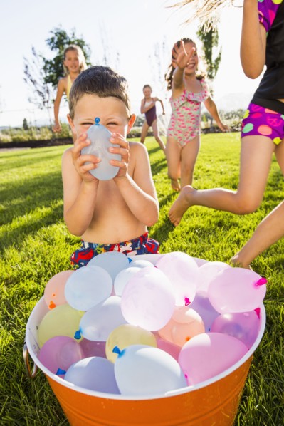 Caucasian children playing with water balloons in backyard