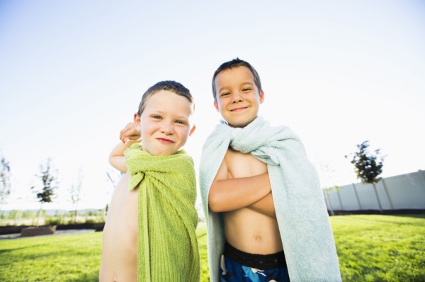 Caucasian boys wearing towel capes in backyard