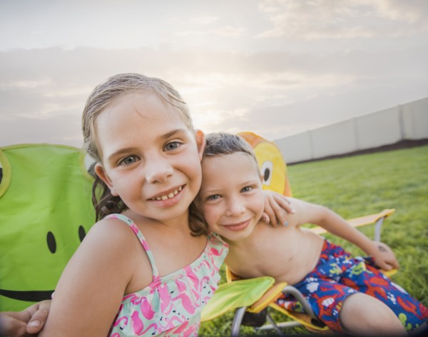 Caucasian children relaxing in lawn chairs in backyard