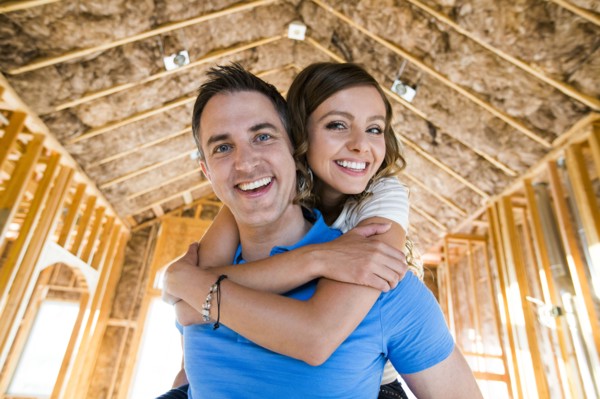 Caucasian couple hugging in house under construction