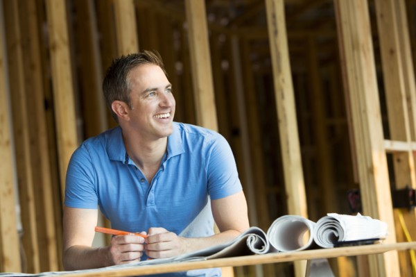 Caucasian man with blueprints in house under construction