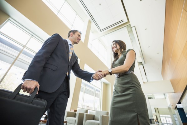 Low angle view of business people shaking hands in office lobby